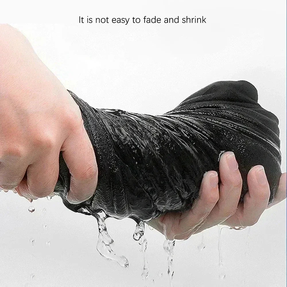 Black cotton hip hop shirt streetwear garment held and squeezed with water dripping from its wet surface