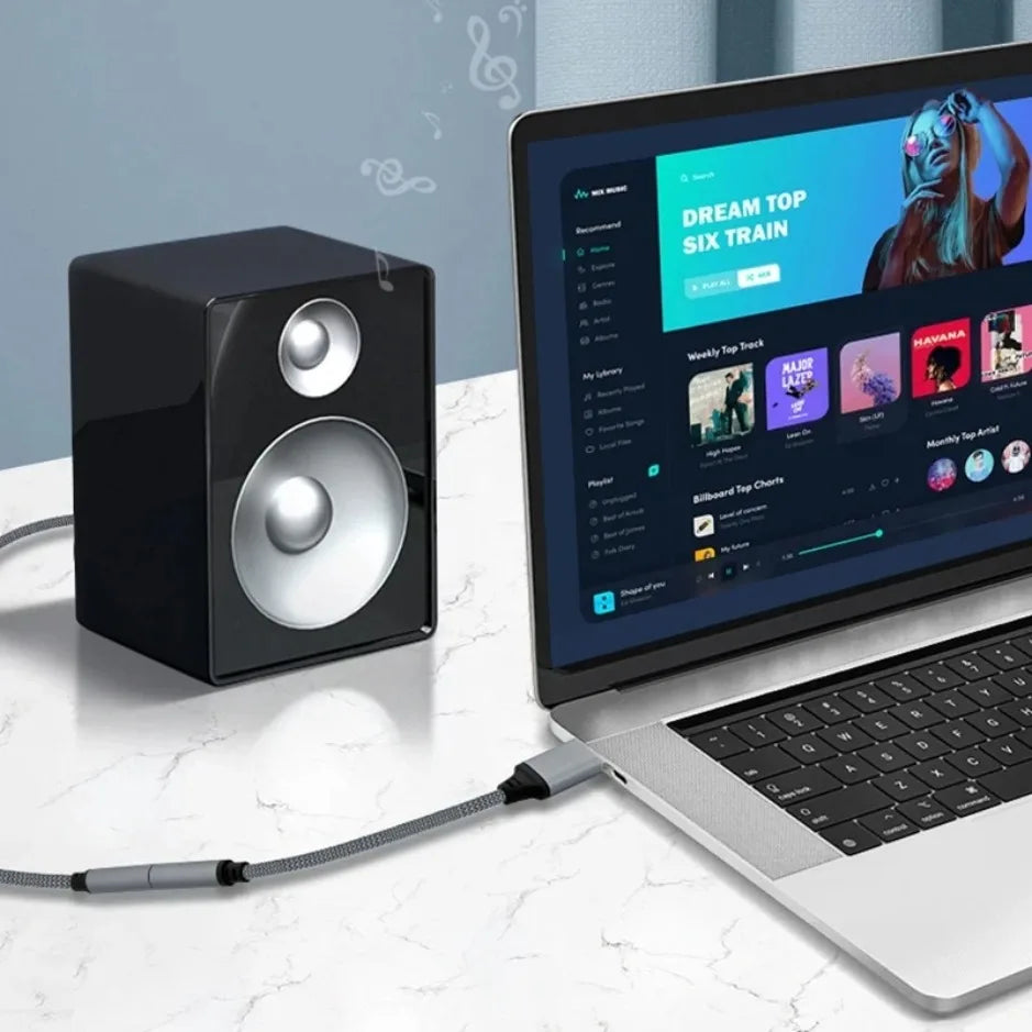 Black and silver studio monitor speaker with glossy finish alongside external sound card adapter headphone micphone 3.5mm audio cable