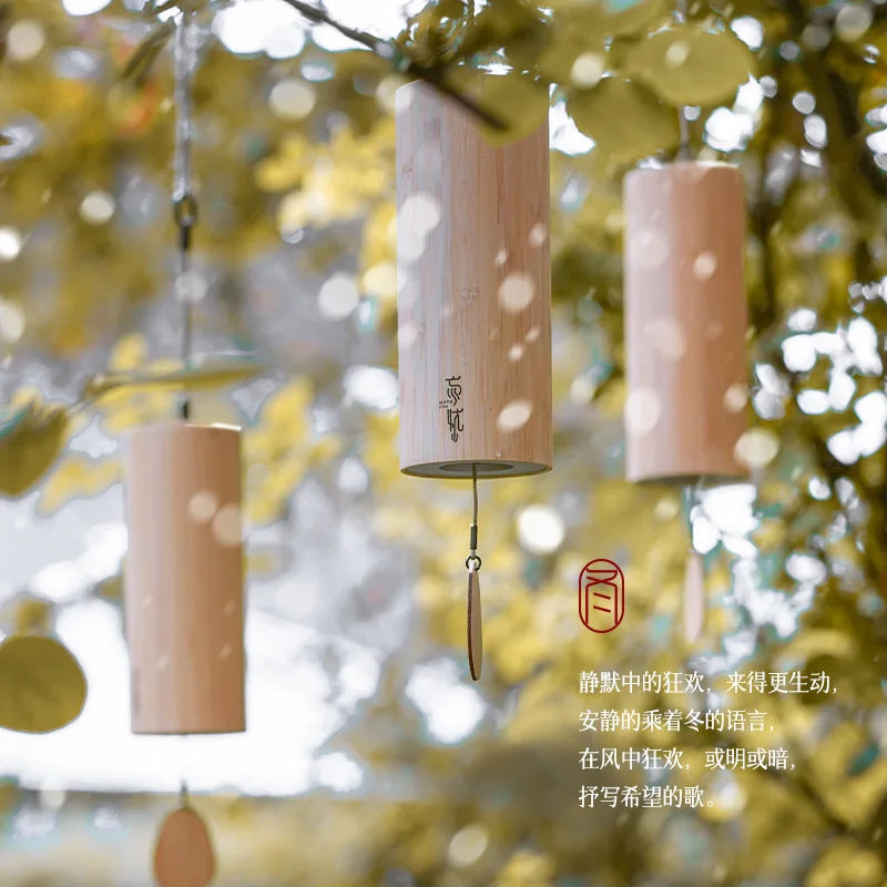 Three cylindrical wooden hand wind chimes with natural finish hang on branches for chime balcony bedroom use portable musical instrument