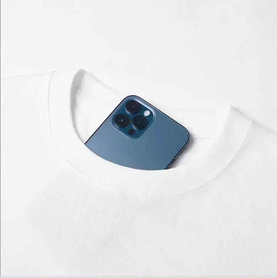 A sleek deep blue iphone 12 pro with triple-lens camera nestled in the neckline of a white cotton short sleeve t-shirt