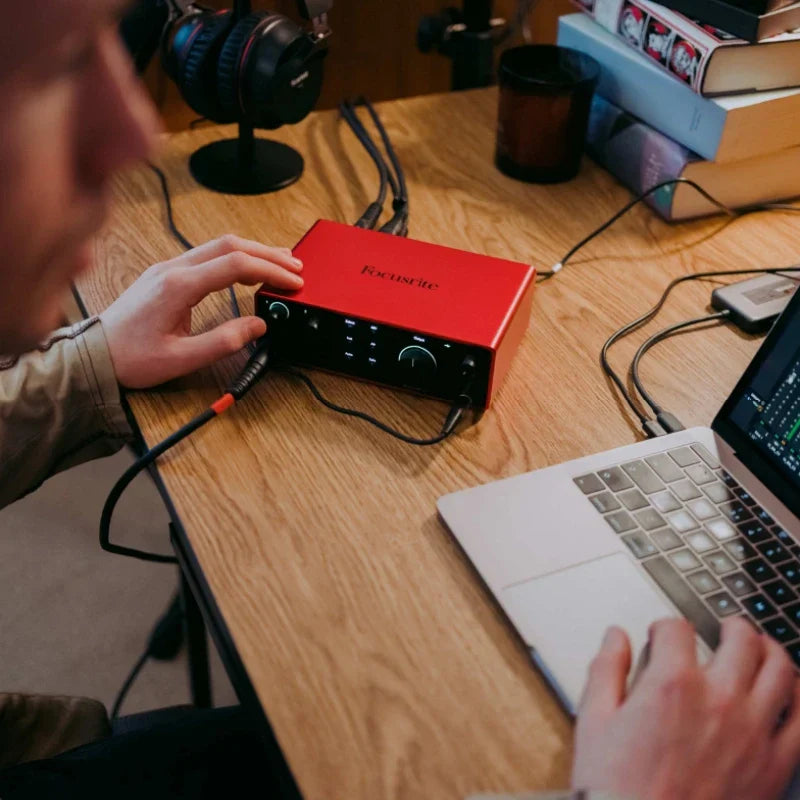 Red focusrite scarlett 2i2 audio interface with black front panel and control knobs as a complete compact studio hub