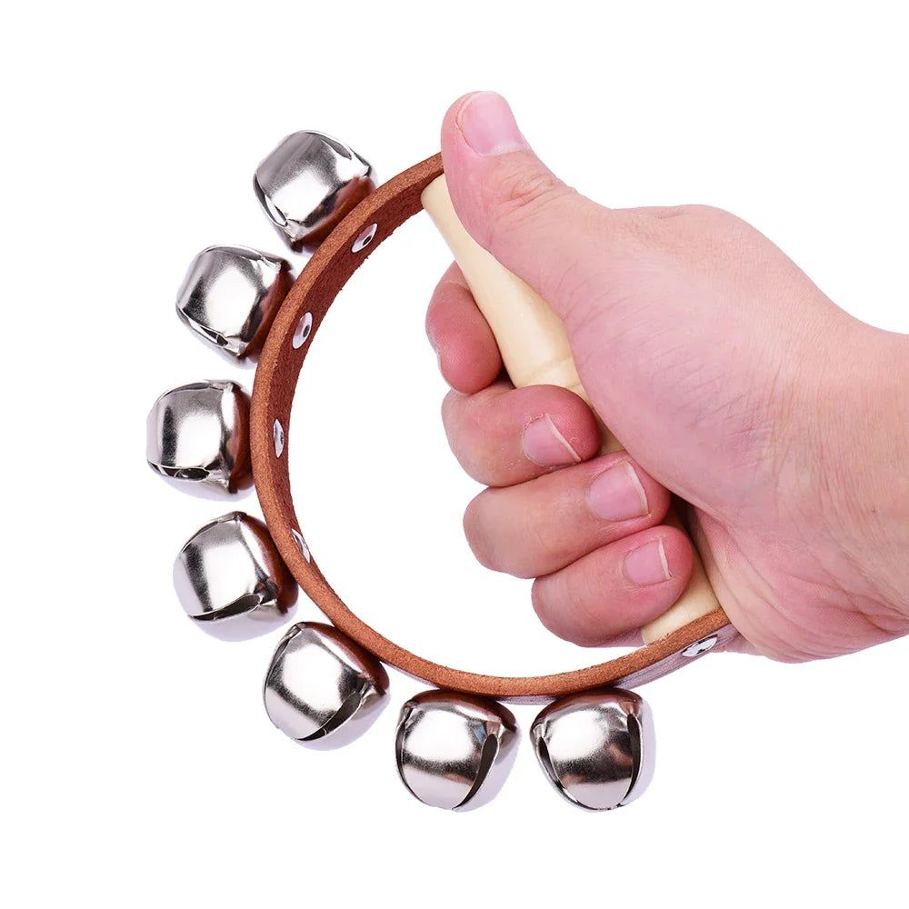 A hand holds a brown leather wrapped handbell hand bells with 7pcs jingle bells and wood handle musical instrument