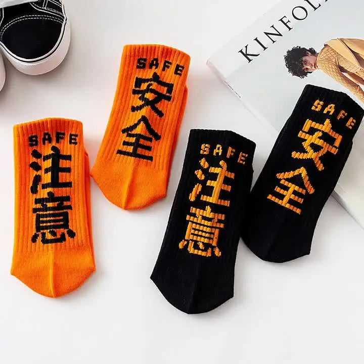 Bright orange and black harajuku tactical socks with bold safe text knitted from soft cotton blend for casual skateboard sock use