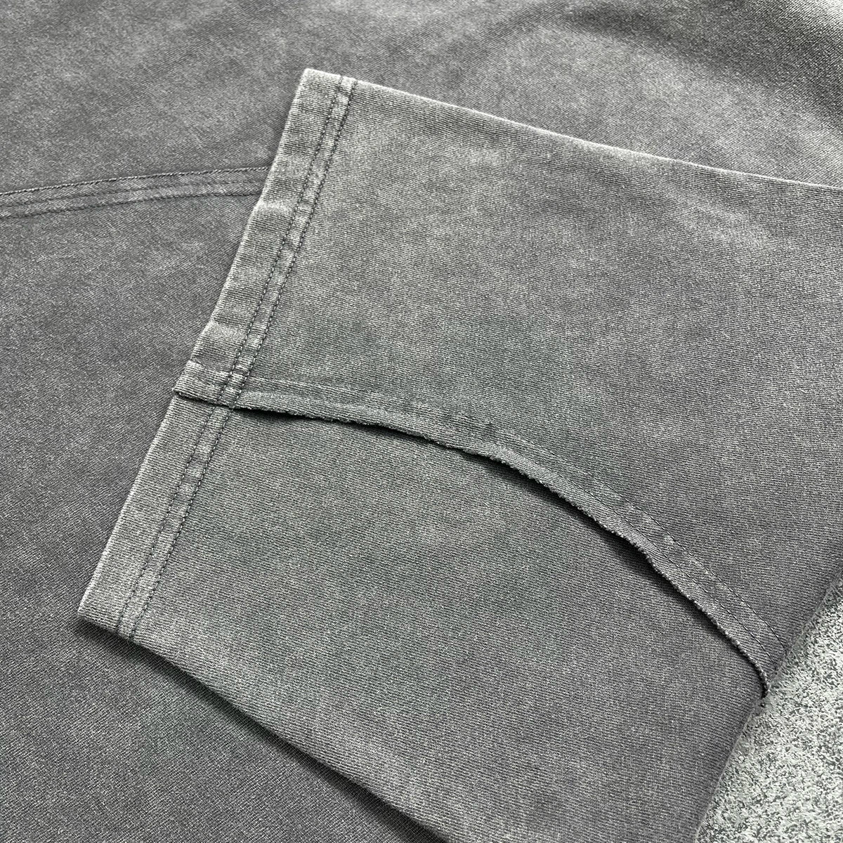 A close-up of dark gray cotton denim fabric with visible stitching on the folded cuff of a sleeve tee oversized quality raw edges
