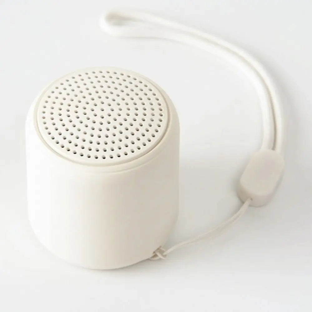 Cream-colored cylindrical karaoke mini bluetooth speaker with perforated top and fabric strap for rechargeable music wireless use