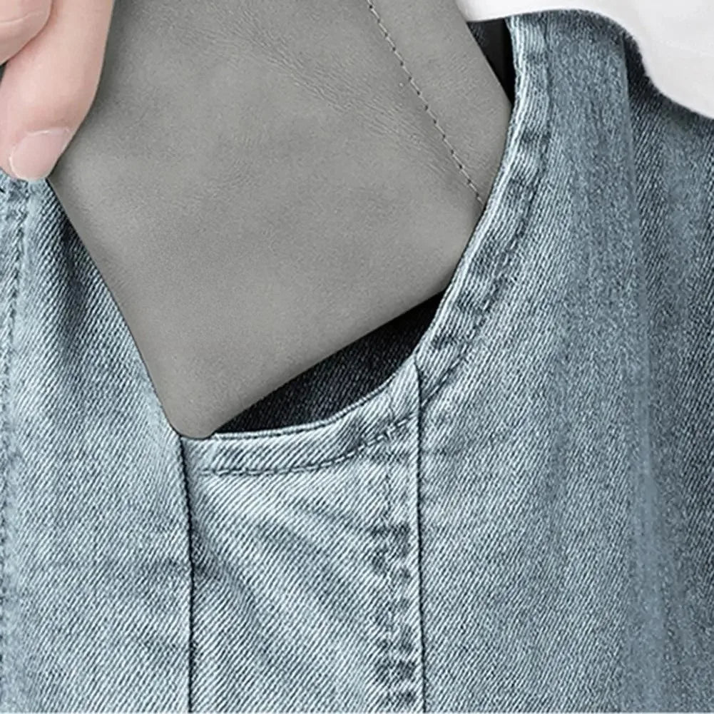 Gray leather mini earphone storage bag with subtle stitching partially tucked in denim pocket pocket waterproof dustproof data cable organizer