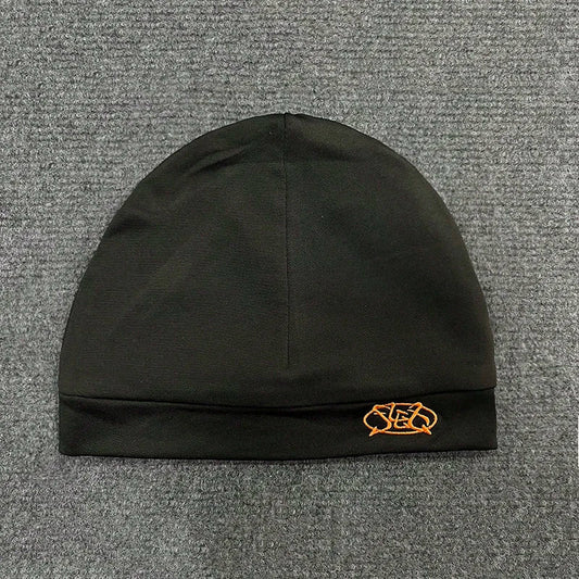 Black knit pullover hat trendy with small orange embroidered letter cap on folded brim for fashionable streetwear