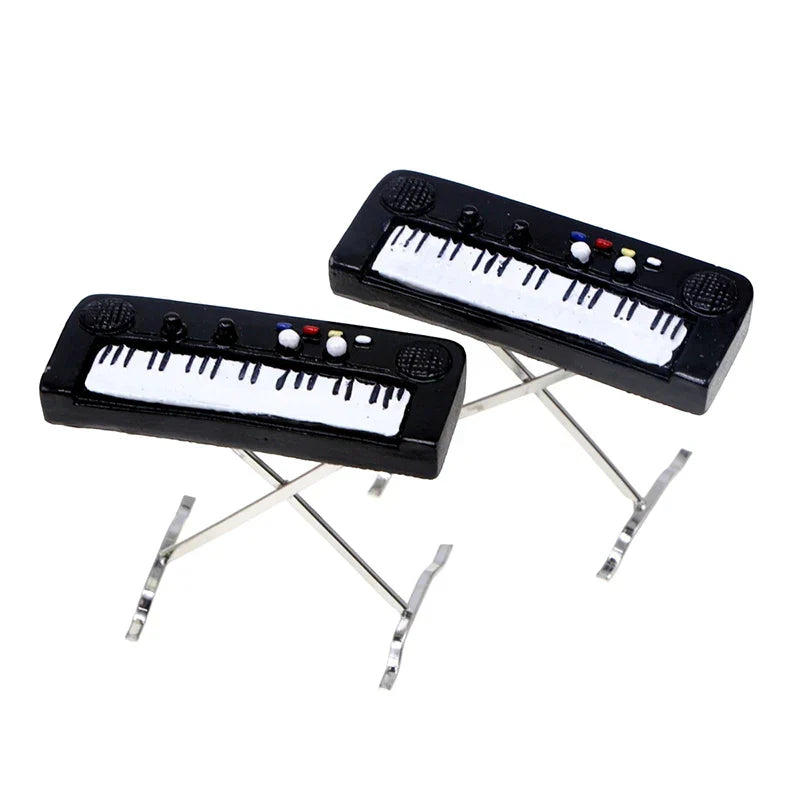 Black miniature electronic keyboard piano with white keys and colorful buttons on silver metal stands for dollhouse decor