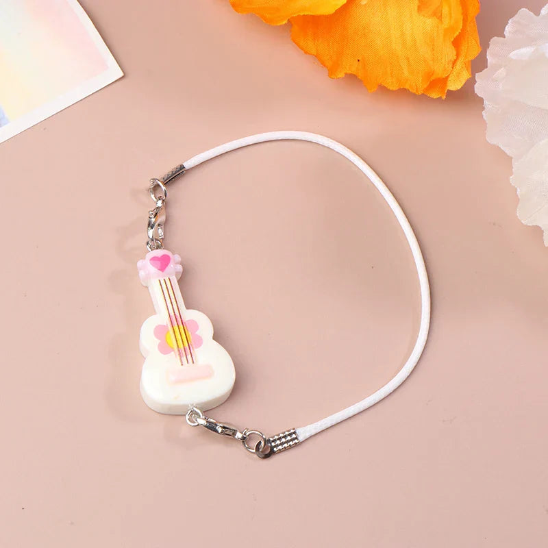 White guitar-shaped charm with pink and yellow floral details on white cord for dollhouse miniature furniture accessory
