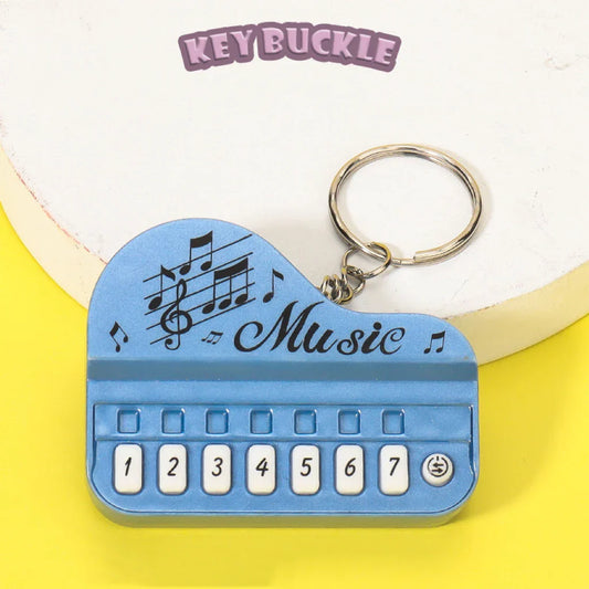Blue piano-shaped mini electronic piano keychain pendant with numbered keys and luminous music toy design