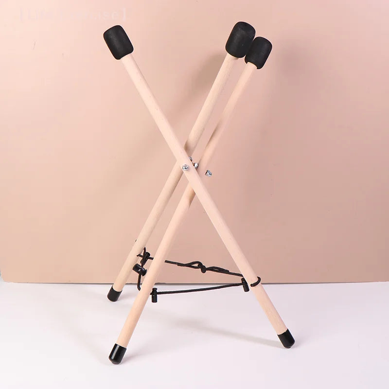 Light-colored solid wood triangle drum stand with black rubber caps for percussion instrument adjustable use