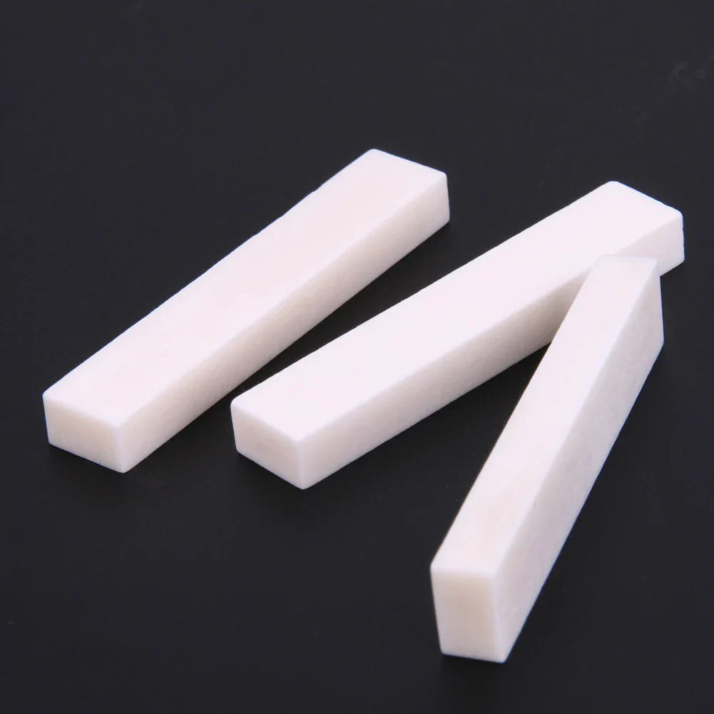 Three white rectangular guitar blank bone nuts with smooth surfaces for professional buffalo bone guitar replacements