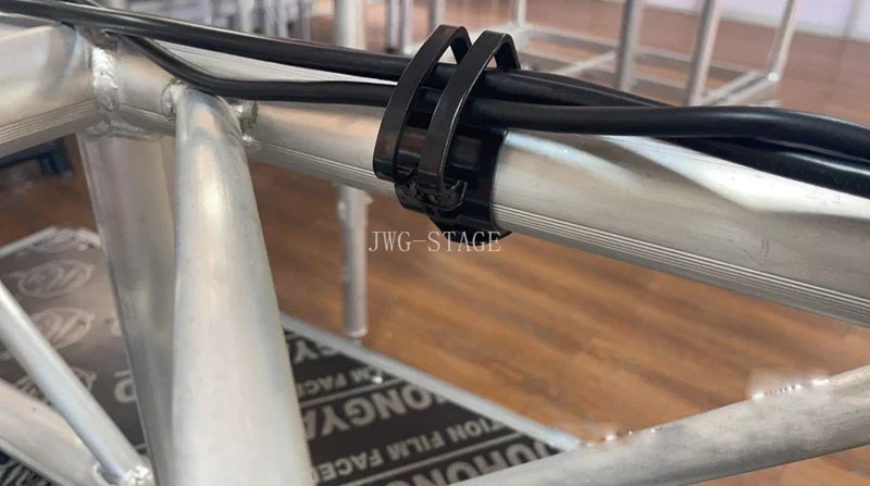 Black lighting wire clip securing black cables to a silver truss aluminum frame for card audio line management