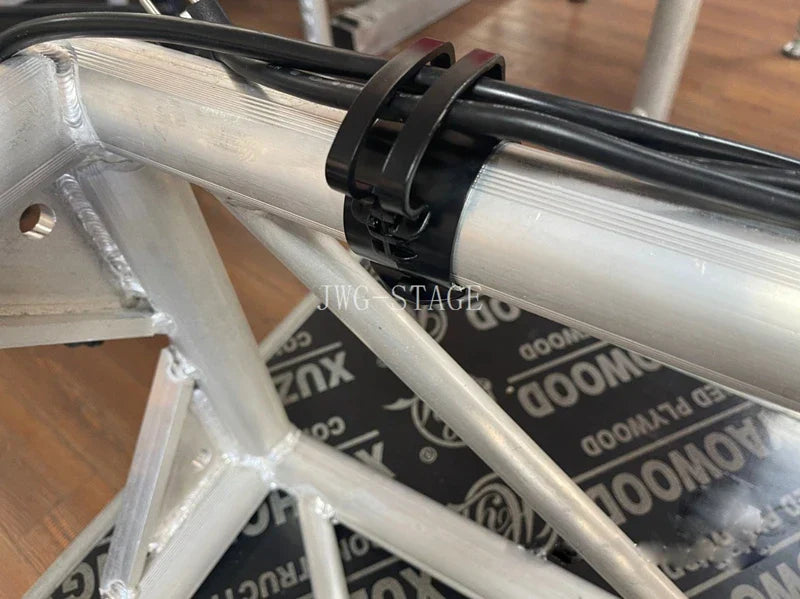 Black plastic lighting wire clips securing cables to silver truss aluminum frame for card audio line management