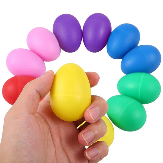 A hand holds a bright yellow plastic egg shaker among colorful percussion musical egg shakers for toddlers baby sensory play