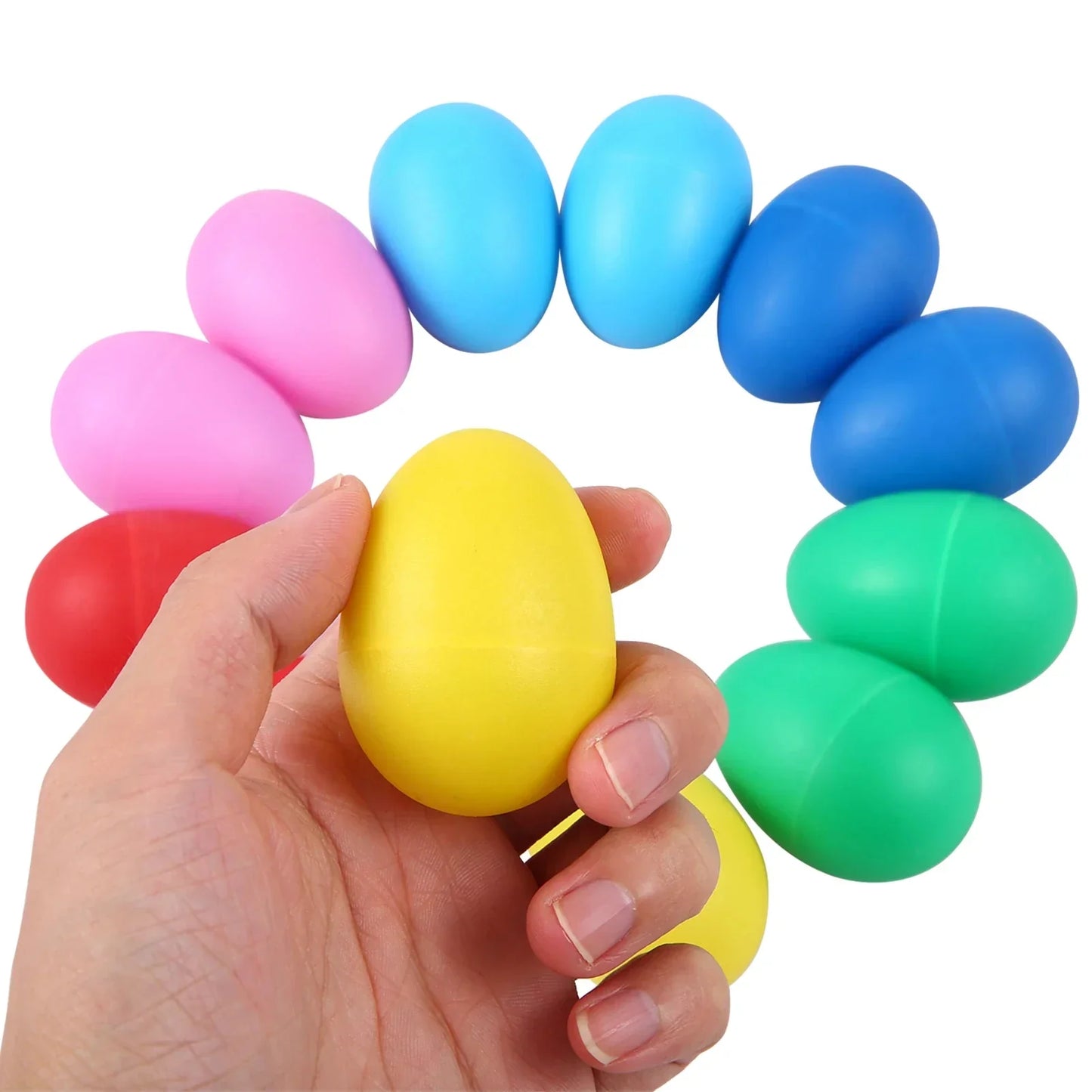 A hand holds a bright yellow plastic egg shaker surrounded by colorful kids toys plastic musical instruments percussion eggs