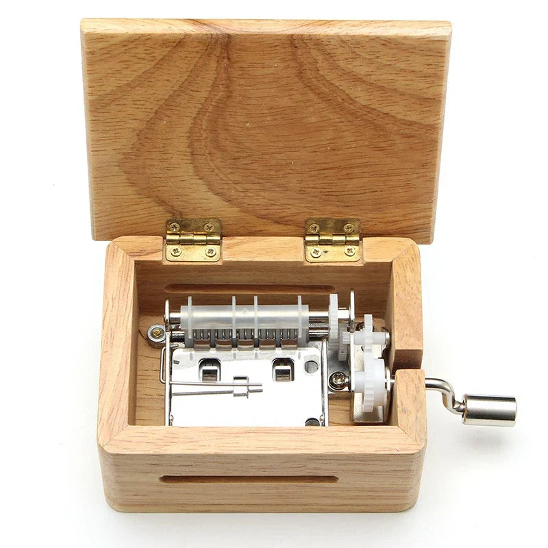 A light-colored wooden 15 30 tone hand-cranked music box with silver crank and paper tape puncher for music paper composing