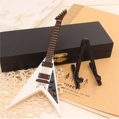 White wooden mini electric guitar with black pickguard on stand beside black case for support miniature model collection