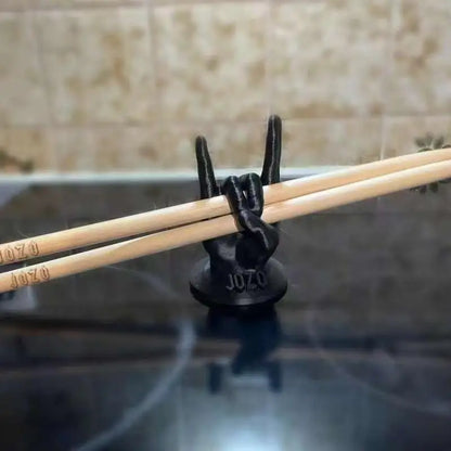 Black metal hand drumstick mallet display holding two light wooden sticks with jozo engraving on base for drummers