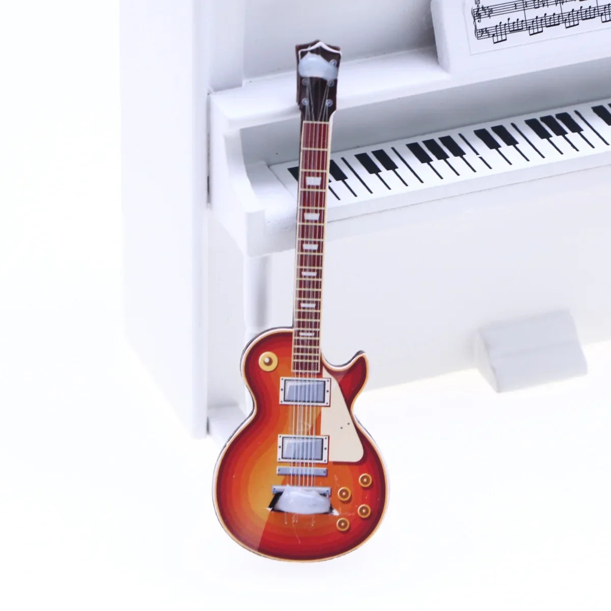 A miniature red and orange sunburst electric guitar with silver hardware and white pickguard for dollhouse mini christmas decor