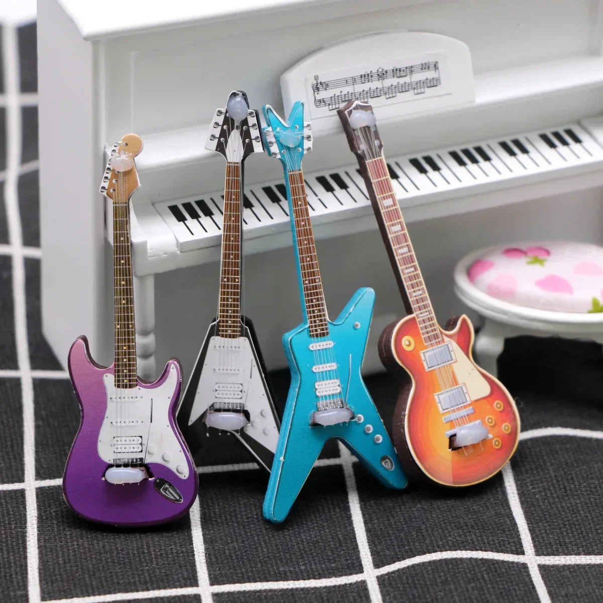 Four vibrant miniature electric guitars in purple black turquoise and orange on checkered surface for dollhouse mini christmas wood grain decor