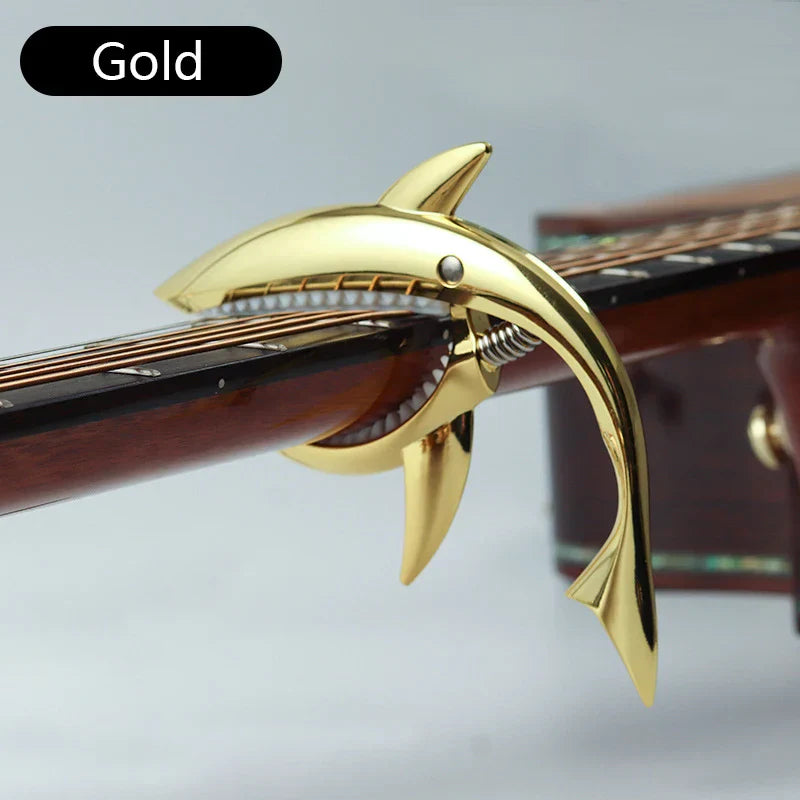Gold metal shark capo with shiny metallic finish and detailed teeth for electric guitar tone and clip bass bridge use