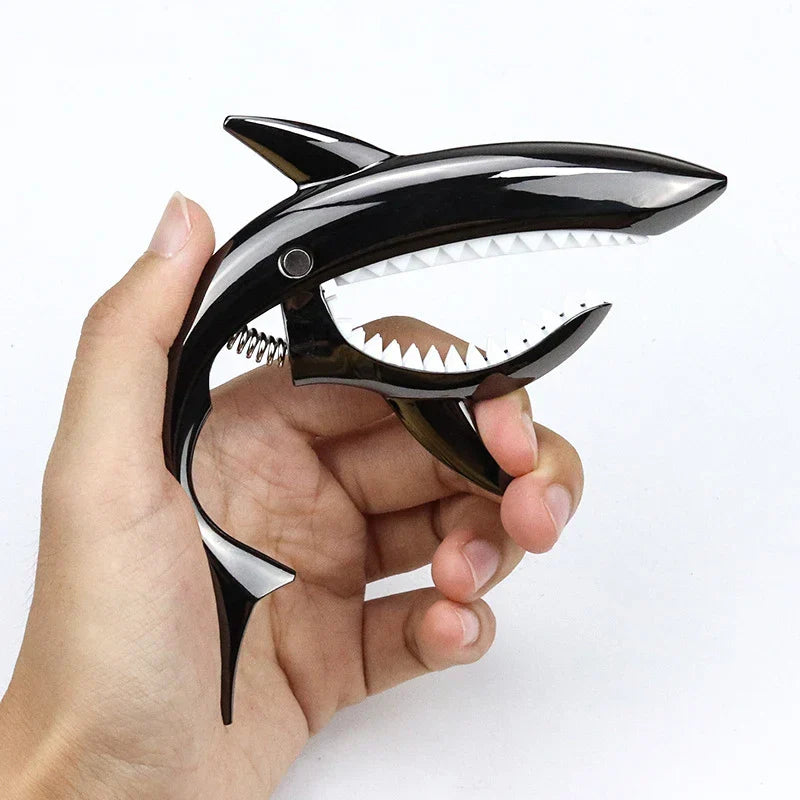 Black metal shark capo with white teeth and spring mechanism for electric guitar tone and clip bass bridge uses