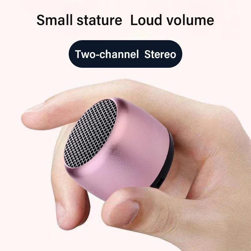 A compact rose gold metal wireless loudspeaker bluetooth speaker portable with black mesh grille and sleek cylindrical design