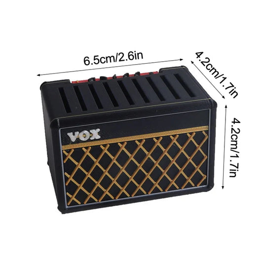Black miniature vox guitar amplifier replica with gold lattice grille and silver logo used as a guitar pick display holder