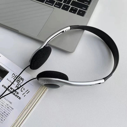 Silver and black wired small headphones with padded earcups resting on a laptop for retro classic headset use