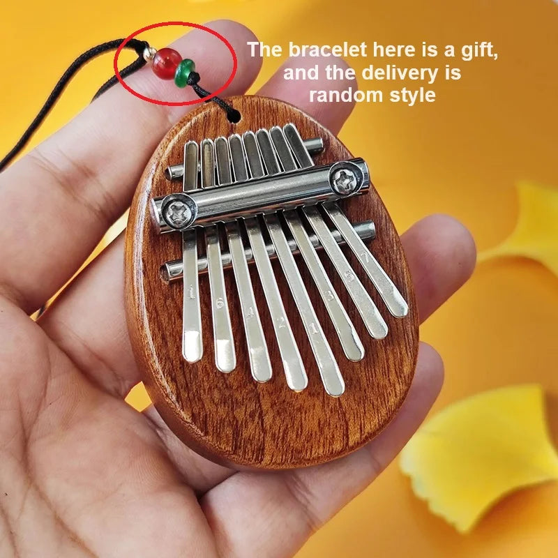 A wooden-handled thumb piano musical toy with silver keys, black cord, and red-green beads for beginner tones portable use