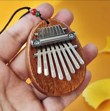 Wooden oval-shaped thumb piano musical with silver metal tines and black cord tones portable beginner finger piano