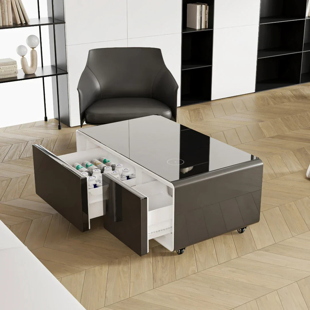 Modern gray smart coffee table with glossy finish, open drawers revealing white shelves for charging mini refrigerator and music speaker