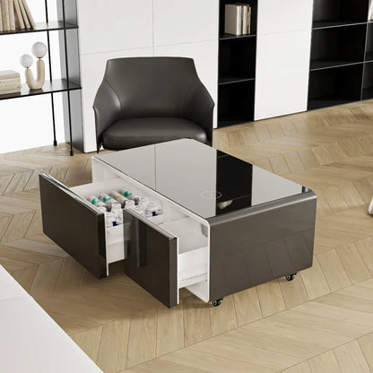 Modern gray smart coffee table with glossy finish, open drawers revealing white shelves for charging mini refrigerator and music speaker