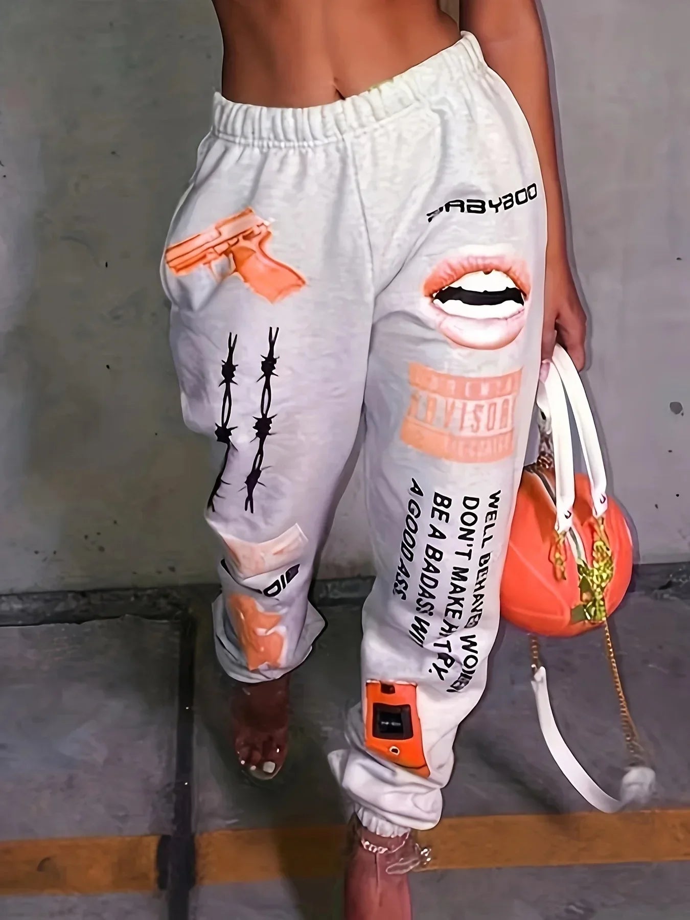 Light gray high waist loose jogger trousers harajuku with bold orange and black graphic sweatpants prints including gun lips and barbed wire