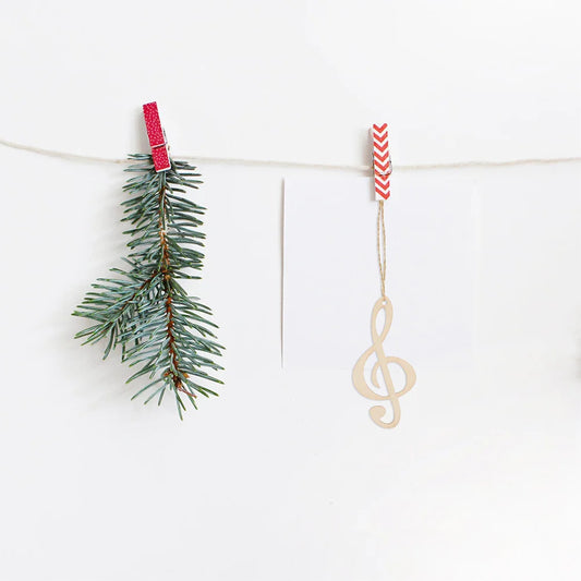 A delicate wood music notes treble clef ornament hanging from a red and white chevron clothespin for concert theme party