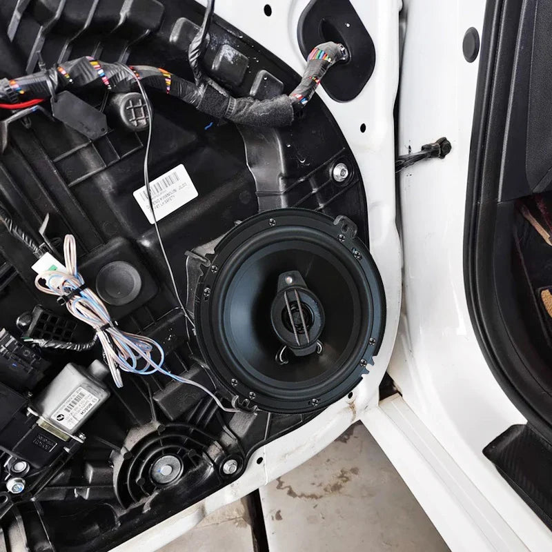 Black circular 6 inch universal car coaxial speaker with central cone mounted in white truck door panel for surround sound