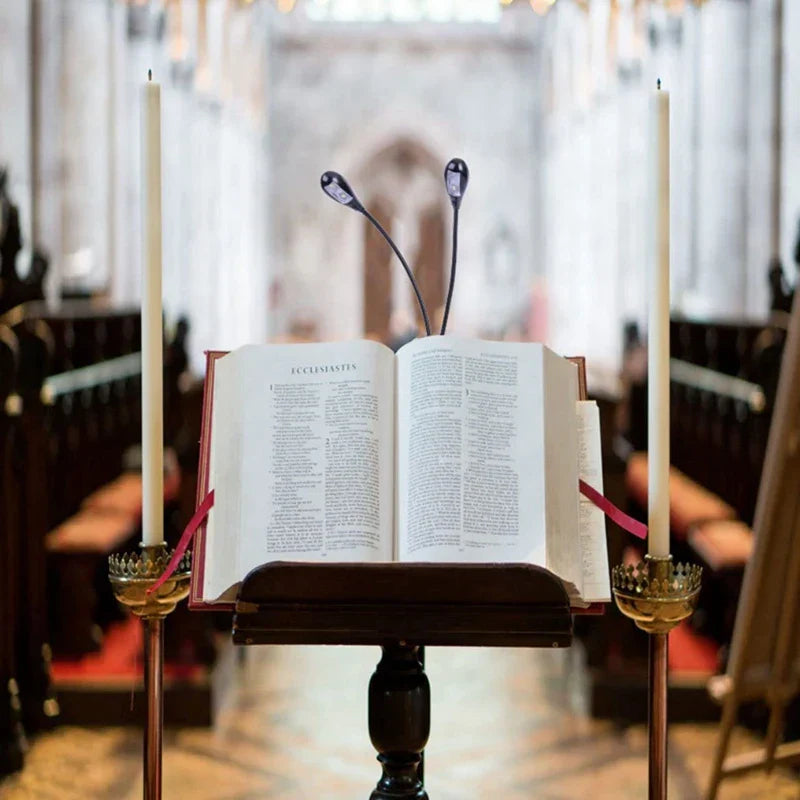 An open red-bound bible on a dark wooden lectern lit by 2pcs led book lights with 360 degree adjustable clip