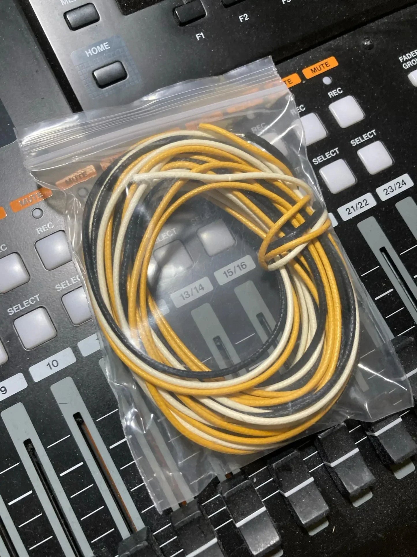 A coiled bundle of yellow and black gavitt fabric pre-dyed 7-strand push 22-watt retro style guitar cords in plastic bag