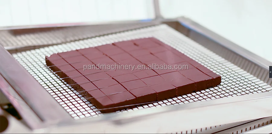 A metal mesh tray holding a square slab of dark chocolate cut using a chocolate double guitar cutter ganache machine