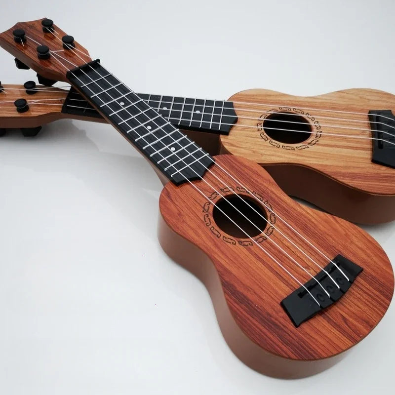 Two wooden 35cm ukulele children guitars with reddish-brown finish and paddles simulating yukrili music toys
