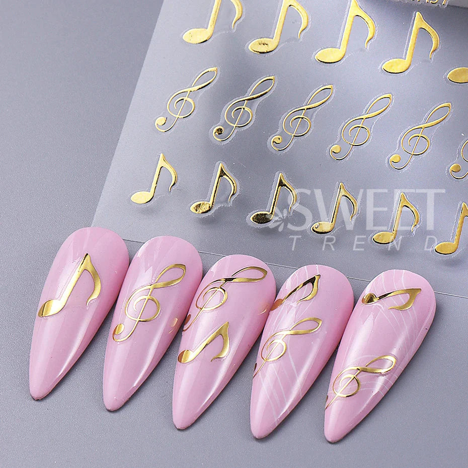Pink marble-finish nails decorated with 3pcs musical notes stickers 3d black and gold y2k metallic holographic design
