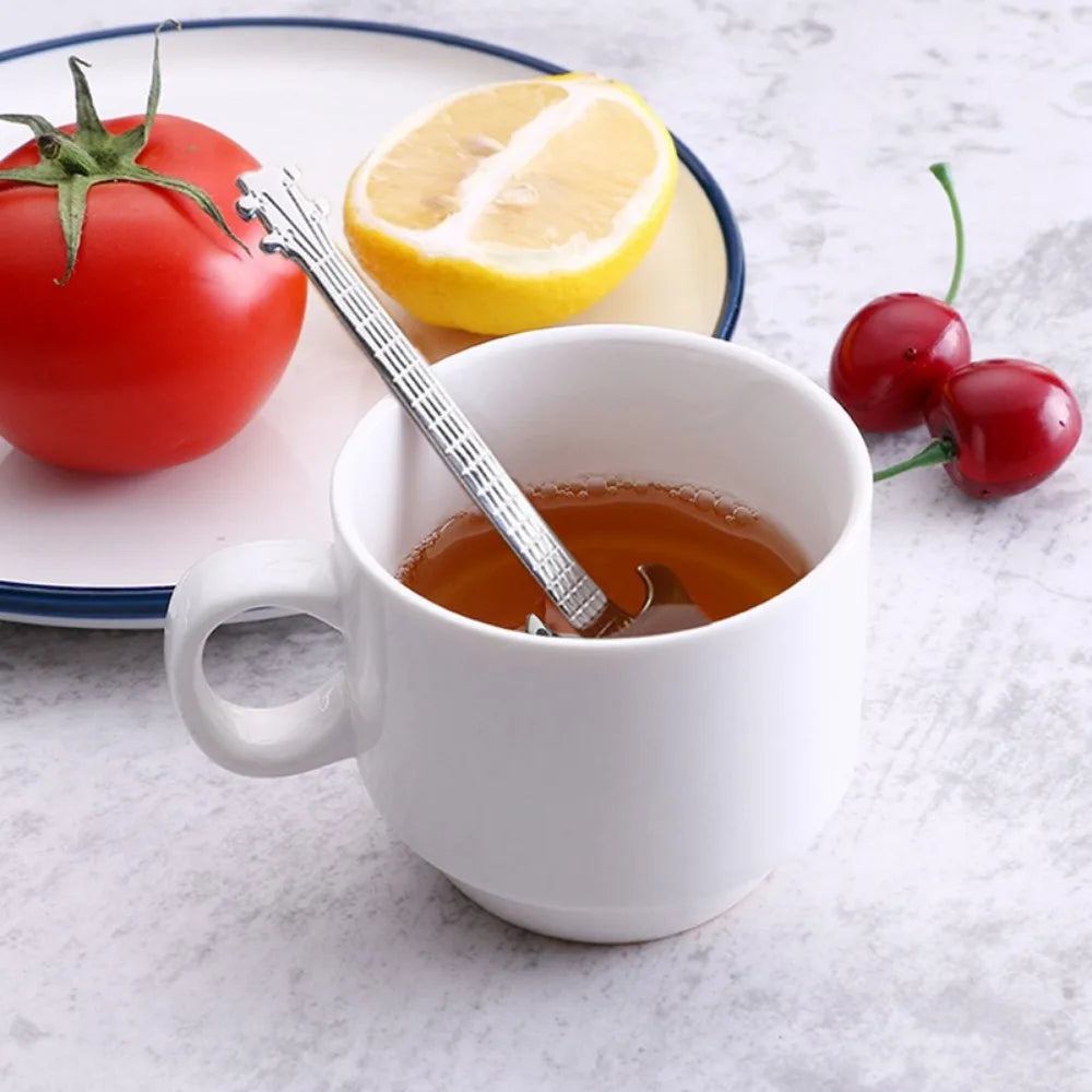 White ceramic mug filled with amber liquid with a silver steel guitar coffee teaspoon inside from 3pcs stainless steel set