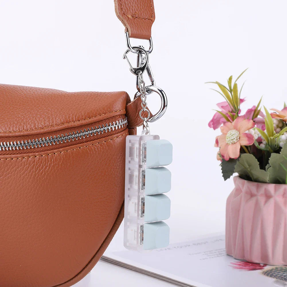A translucent light blue keycap fidget keychain with three pill-shaped compartments for keyboard clicker toy use