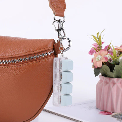 A translucent light blue keycap fidget keychain with three pill-shaped compartments for keyboard clicker toy use