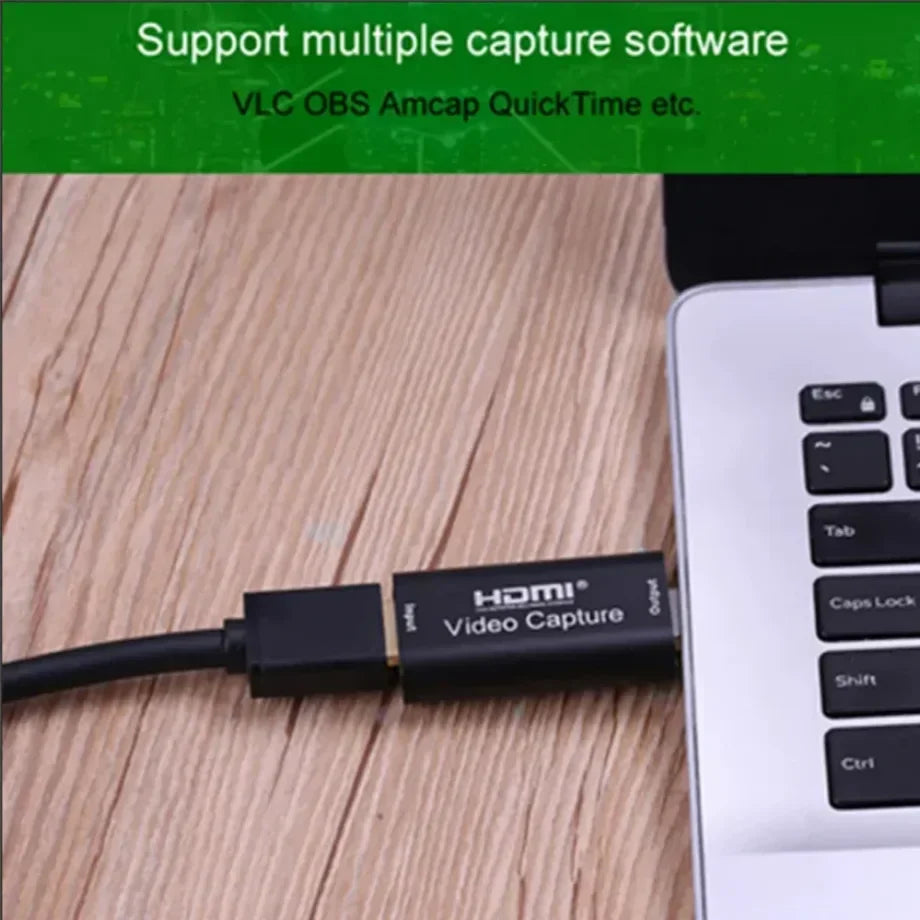 Black hdmi video capture adapter with hdmi video capture label connected to laptop for video live streaming and camera pc recording
