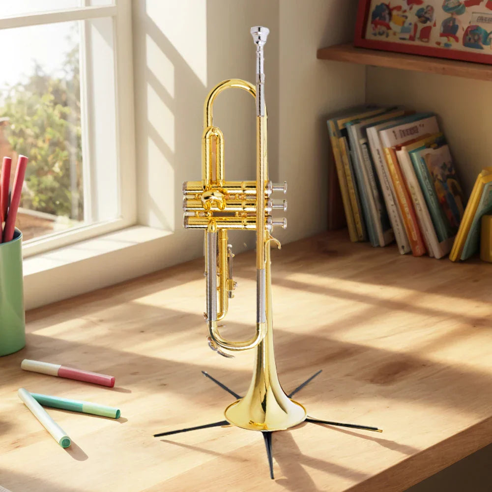 Shiny gold trumpet with silver accents standing upright on a black foldable trumpet stand portable placement rack