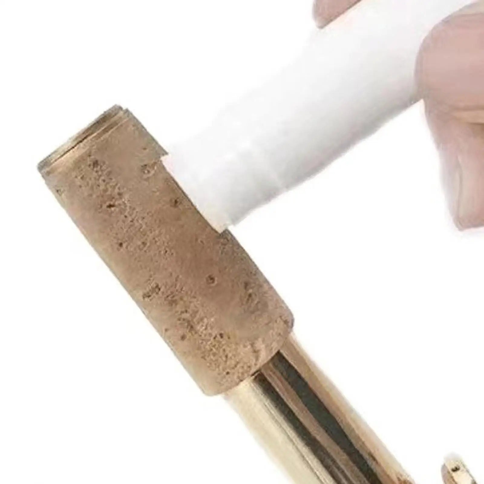 A natural cork stopper with an earthy brown surface being applied to a brass musical woodwind instrument clarinet saxophone using tubes cork grease