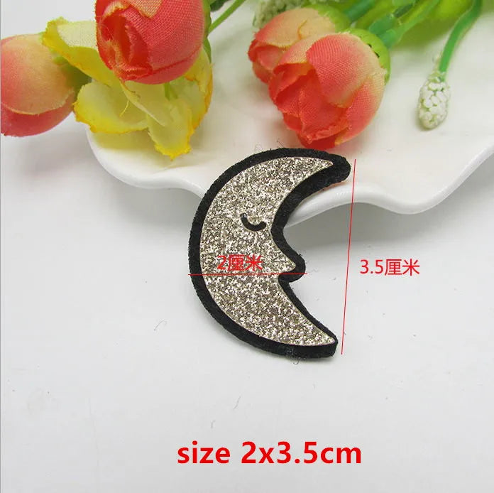 A glittery silver crescent moon sparkle patch padded with a black border and closed-eye design for applique decoration diy