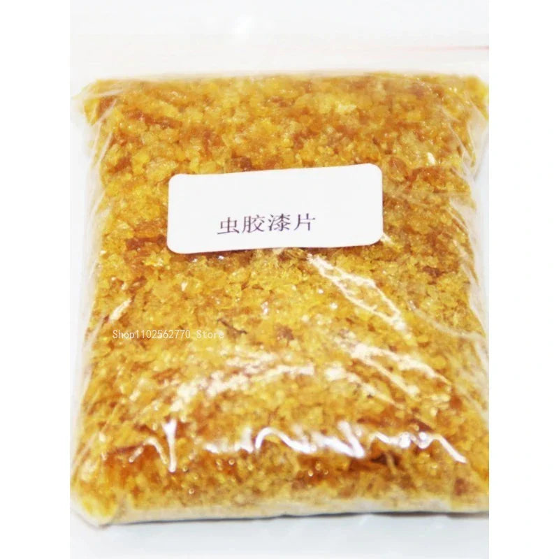 A clear plastic bag of golden-yellow translucent resin flakes labeled in chinese used as 50g shellac varnish for primer handmade guitar material